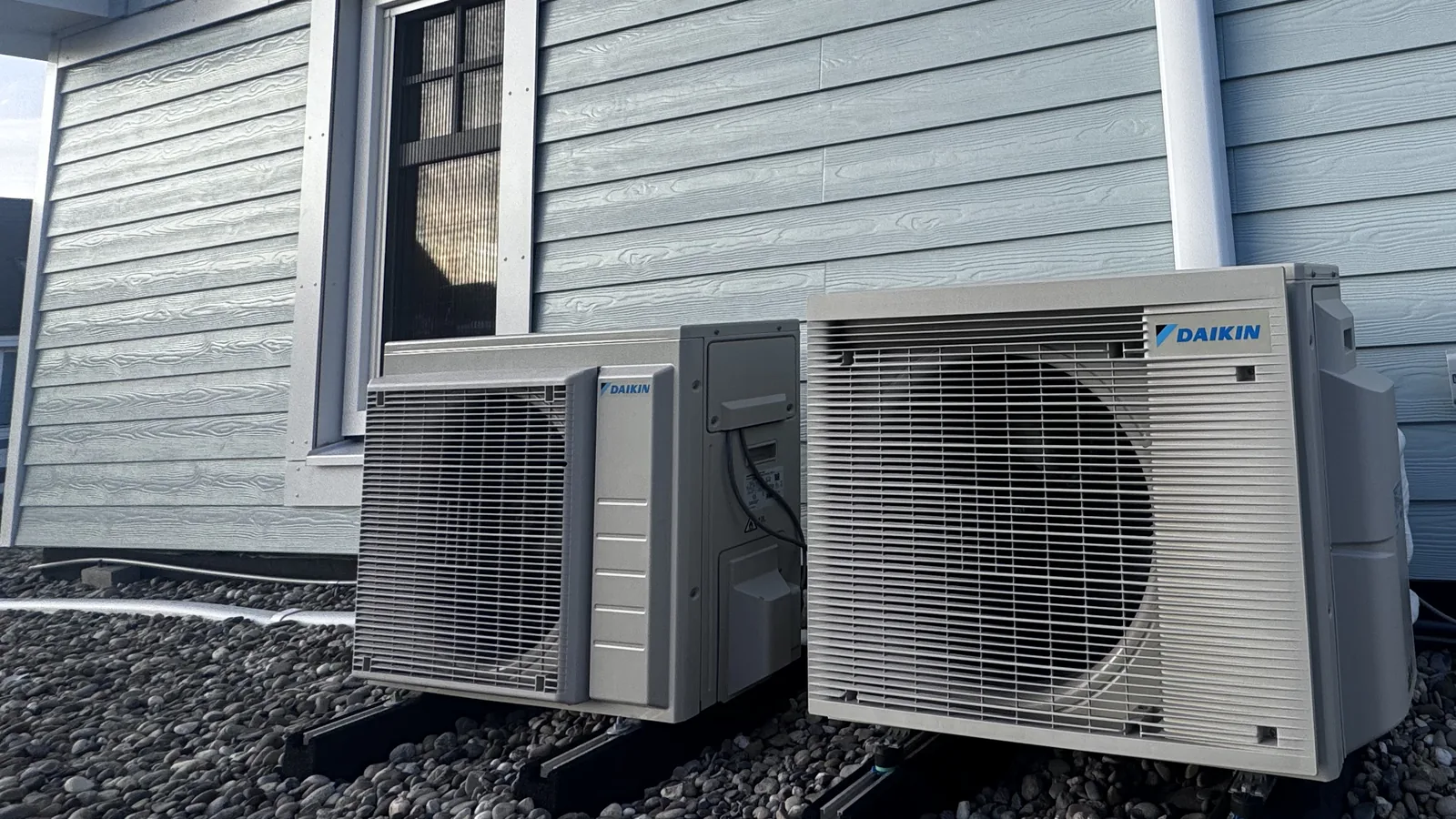 Daikin buitenunit van een airco tegen een blauwe houten gevel