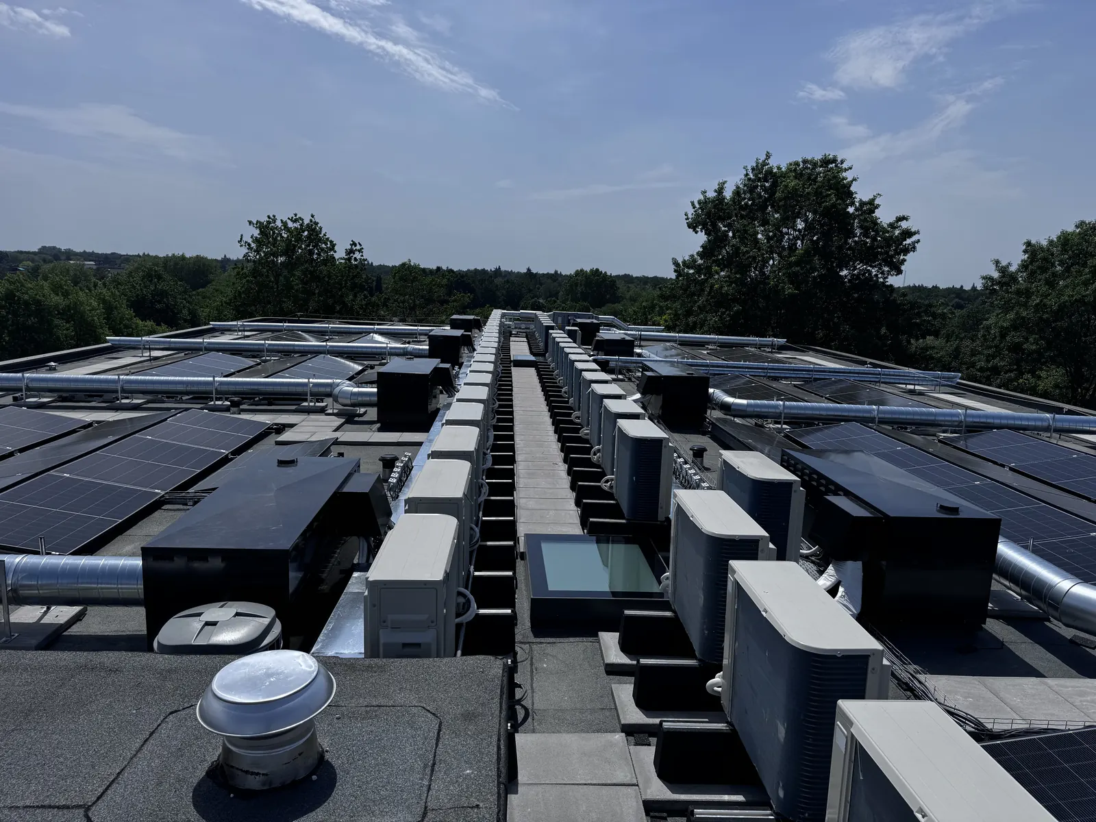 Dak met buitenunits van warmtepompen naast zonnepanelen