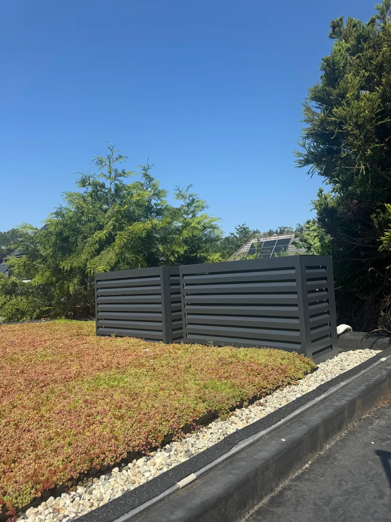 Omkasting voor buitenunits op een sedumdak. Twee buitenunits op een sedumdak kregen een antracieten omkasting met open lamellen. Uitgevoerd door HEAT Nederland.