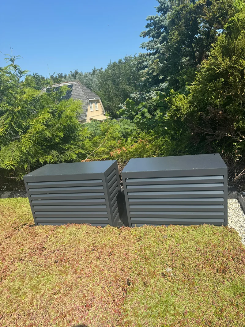 Omkasting voor buitenunits op een sedumdak. Twee buitenunits op een sedumdak kregen een antracieten omkasting met open lamellen. Uitgevoerd door HEAT Nederland.