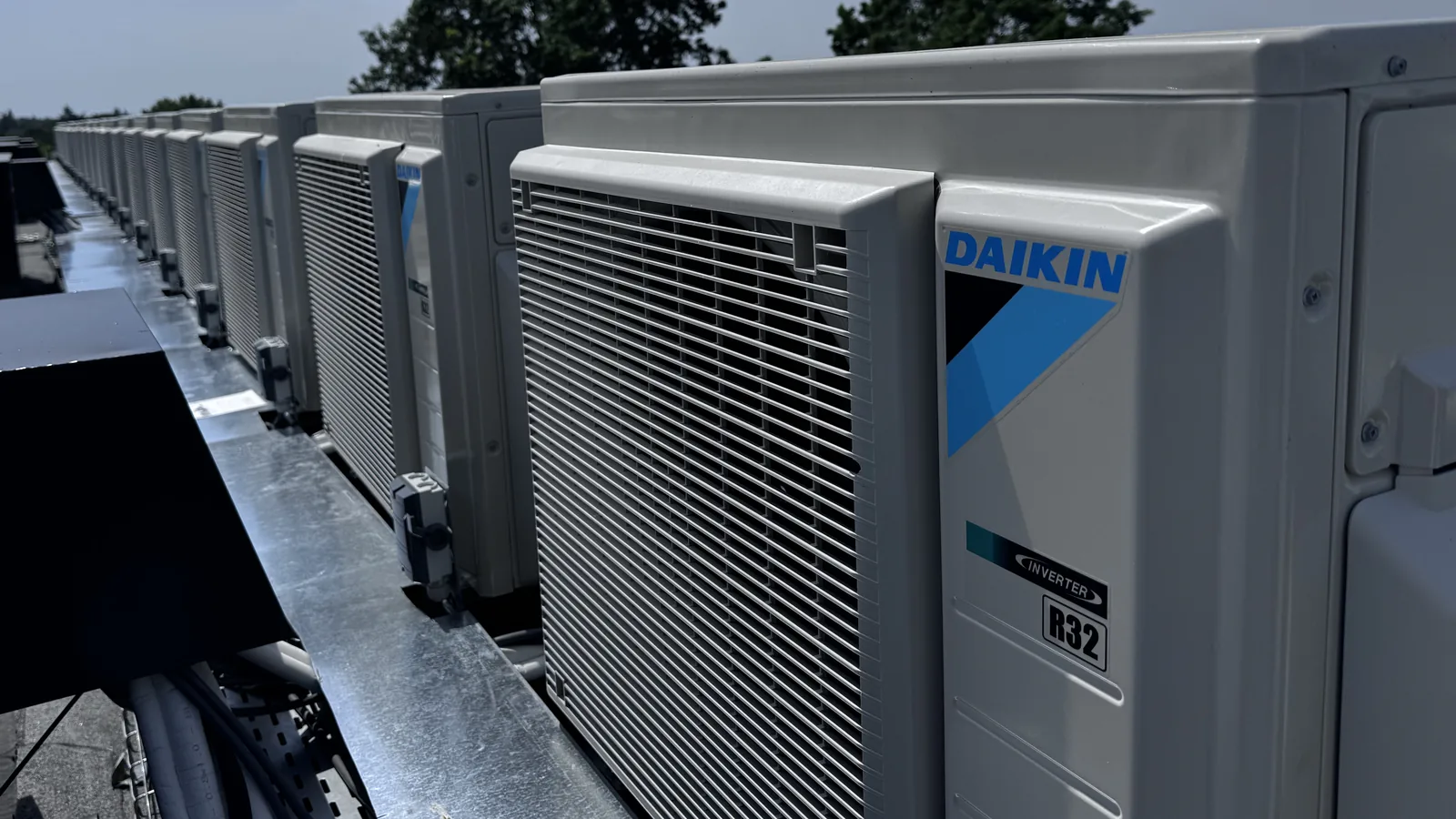 Rij Daikin warmtepompen op een dak, met het Daikin-logo duidelijk zichtbaar